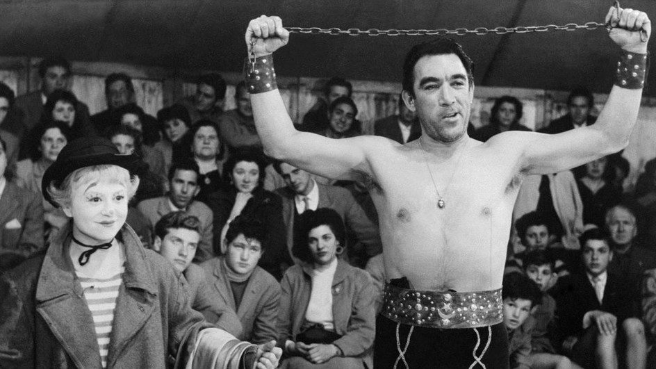 Une fillette au maquillage de clown et un homme torse nu qui montre sa force